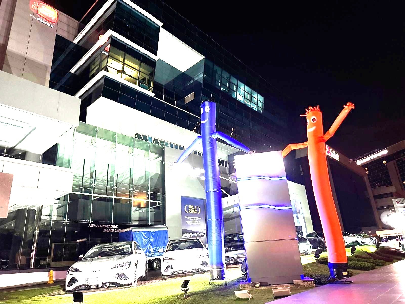 Air dancer rental Singapore with blue and orange figures outside a car showroom at night