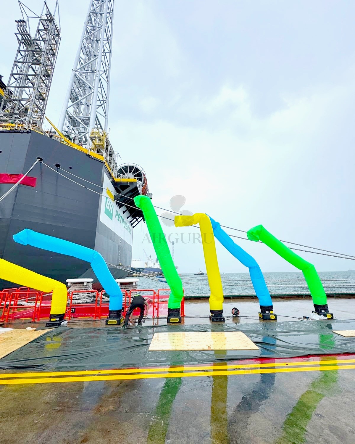Colourful air dancers beside a ship at an outdoor event with Airguru watermark