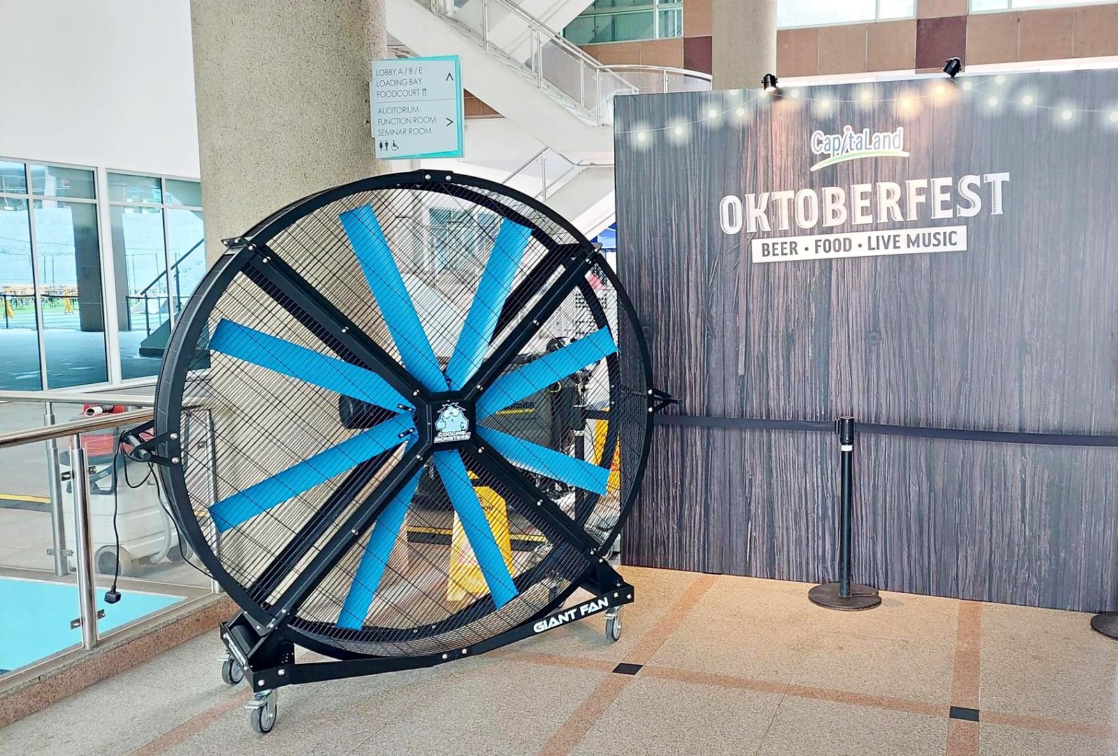 Blue-bladed giant fan beside an Oktoberfest event welcome sign