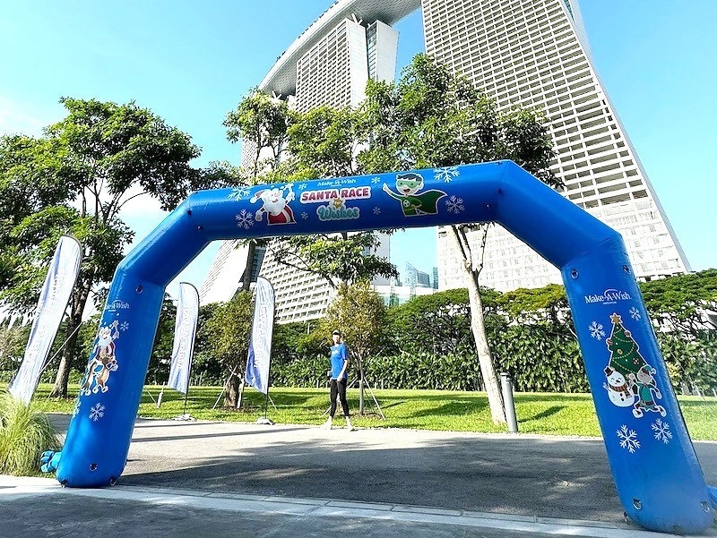 Angled view of a blue branded race arch beside trees