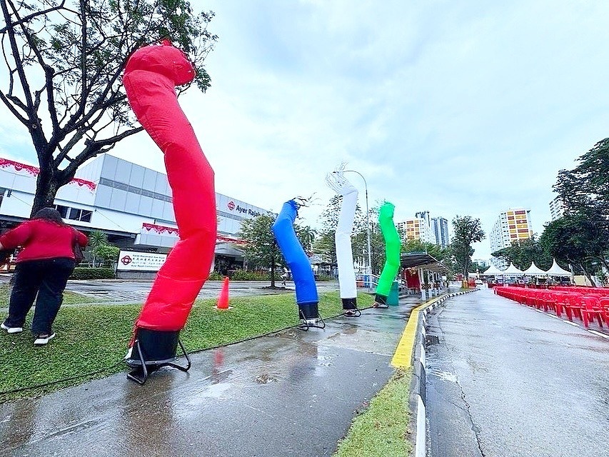 Red blue and green air puppets beside an outdoor event seating area