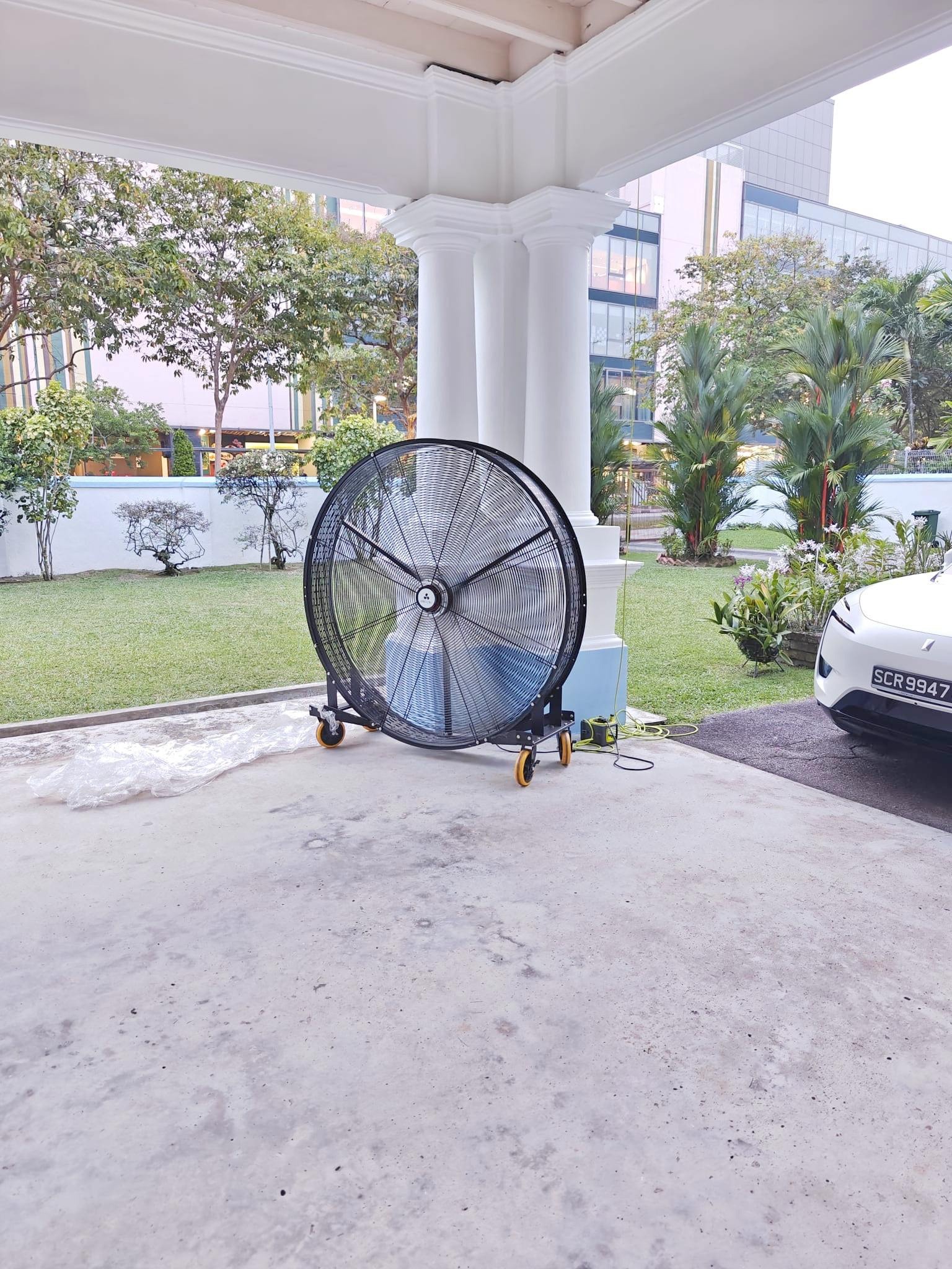 Large floor fan beside a covered entrance with a lawn beyond