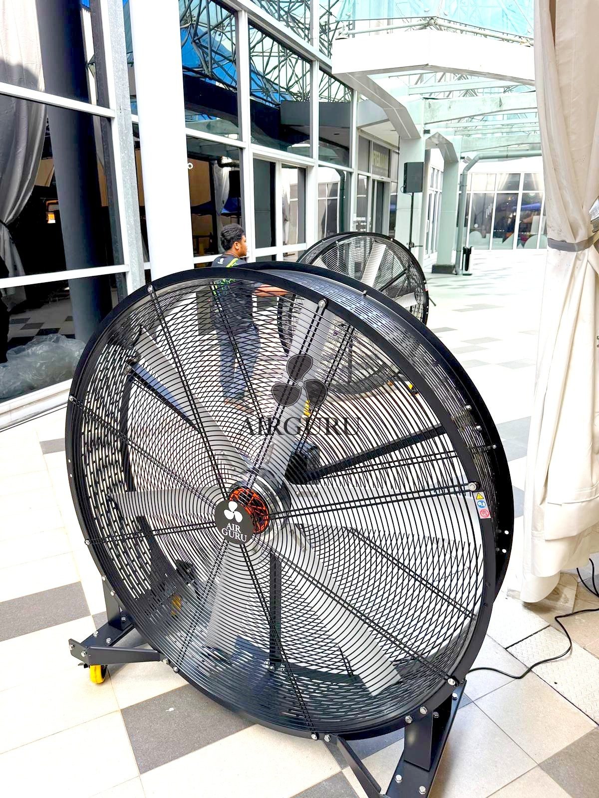 Close view of an Airguru giant fan beside windows in a covered corridor