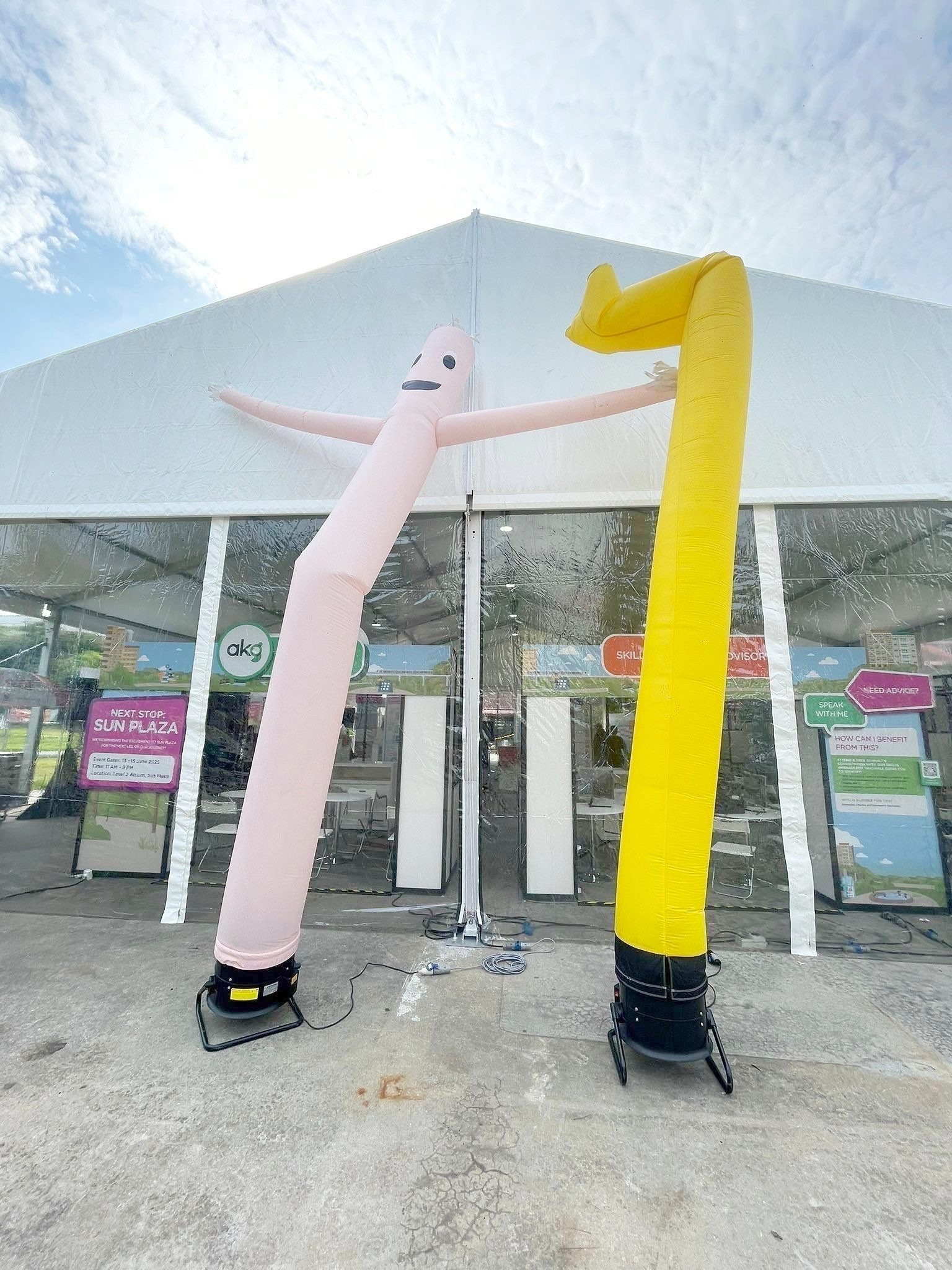 Pale pink and yellow air dancers outside a marquee