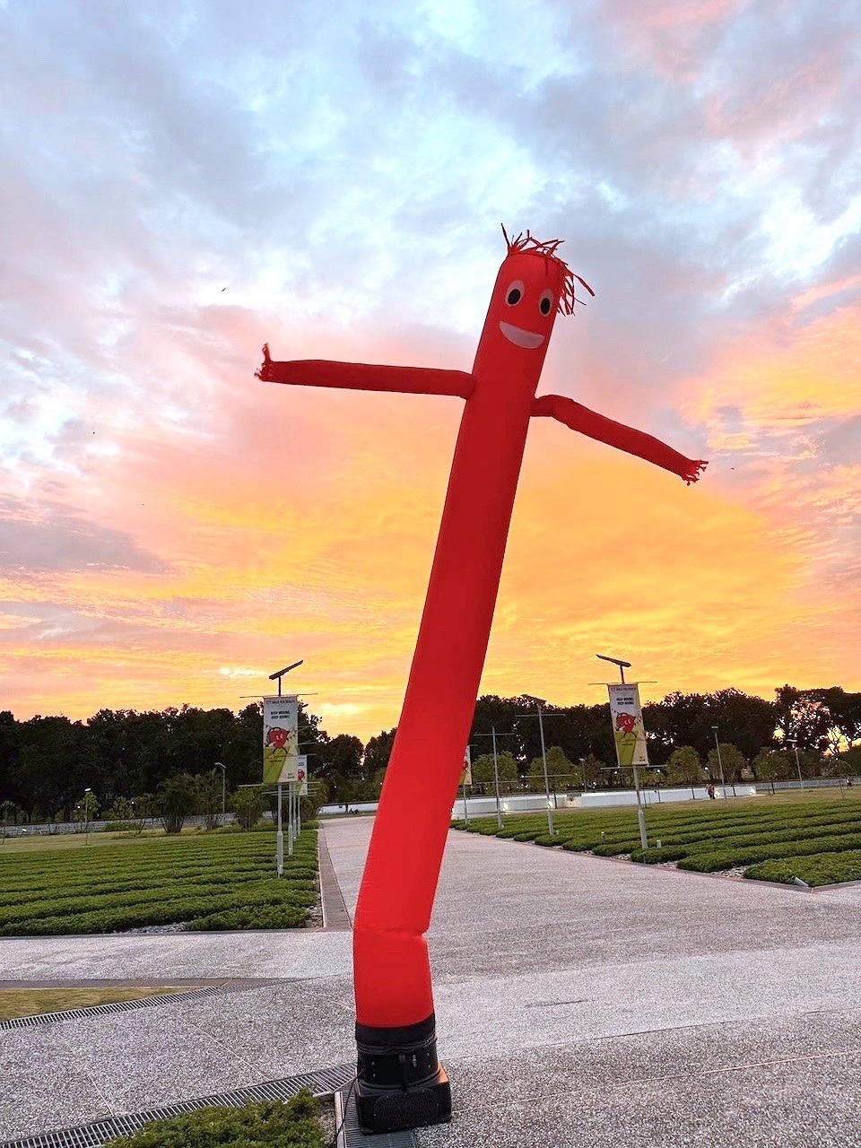 Red air dancer against a sunset sky at an event venue