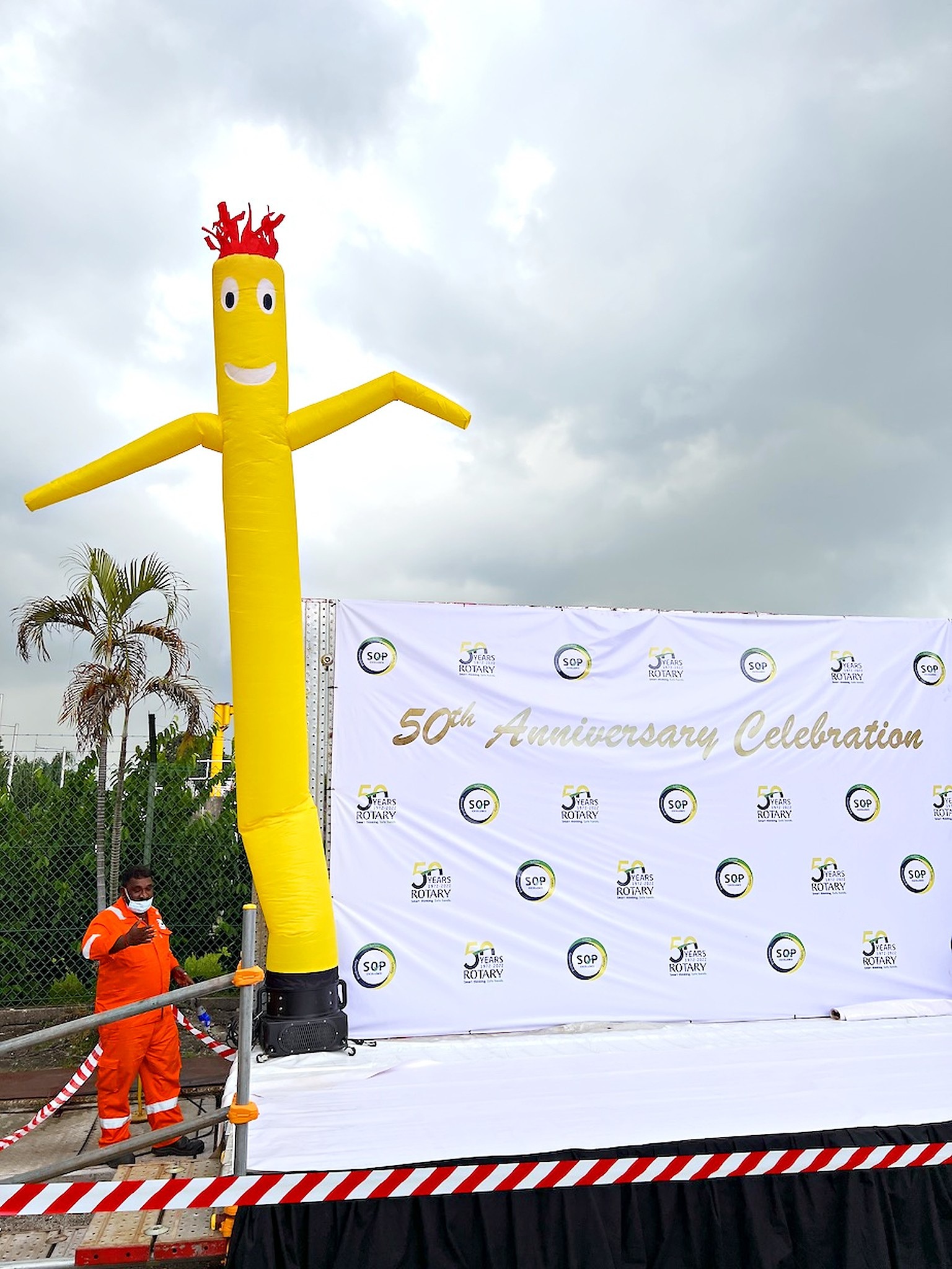Yellow air dancer beside an anniversary celebration backdrop