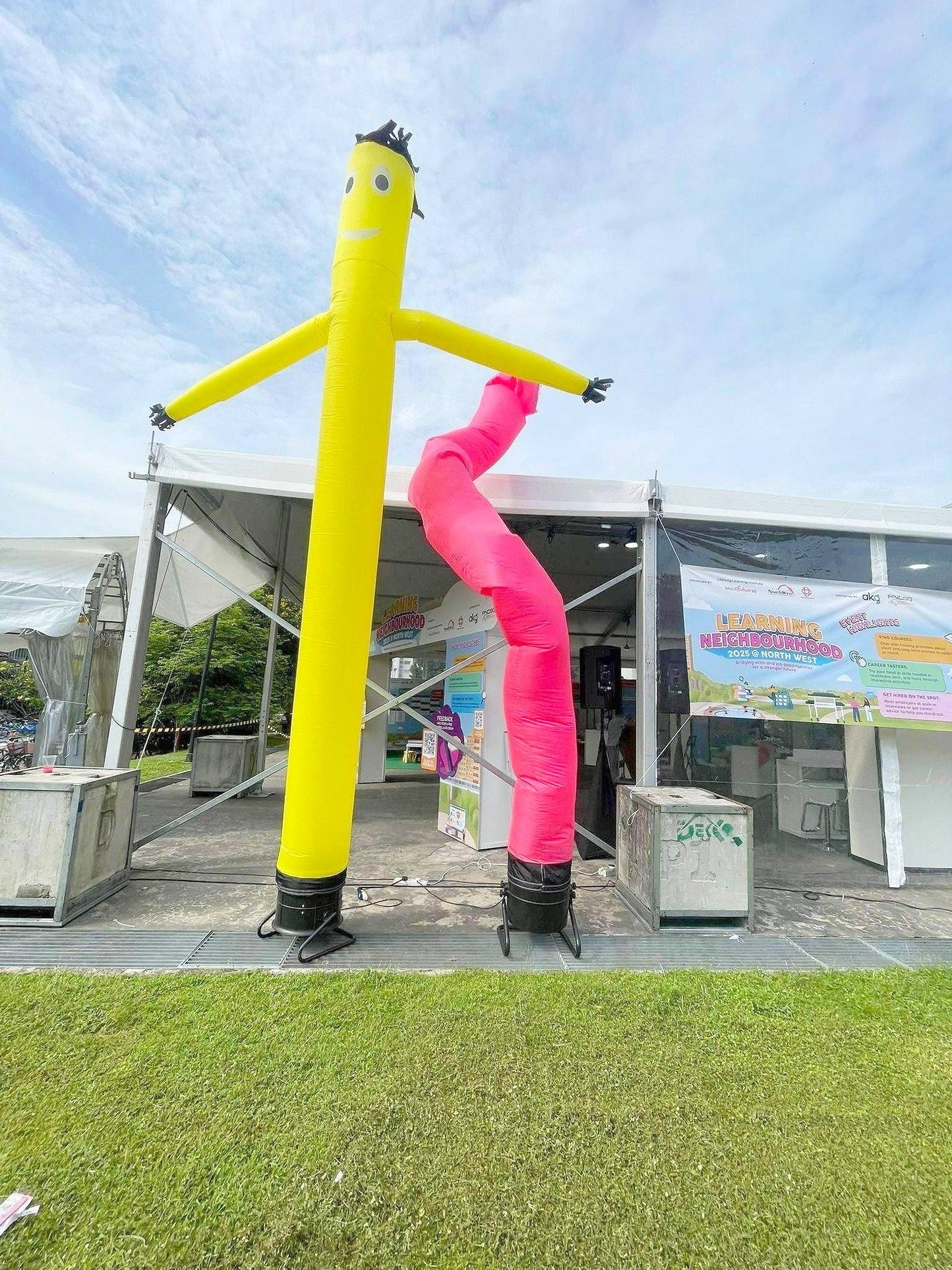 Yellow and pink air dancers beside a community event tent